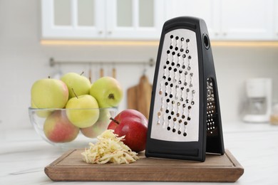 Photo of Grater and fresh ripe apples on white table in kitchen