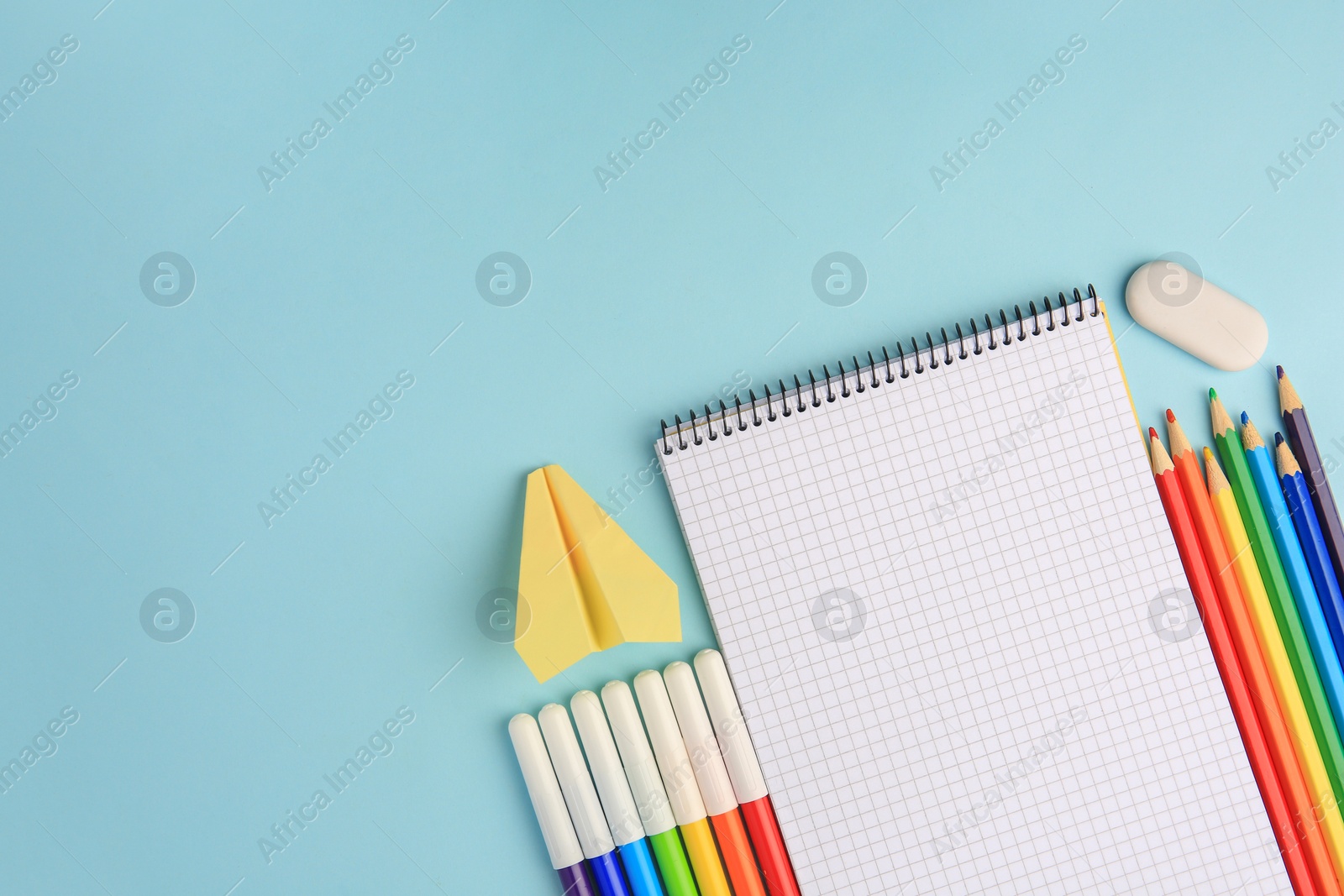 Photo of Flat lay composition with open notebook and other school stationery on light blue background, space for text. Back to school