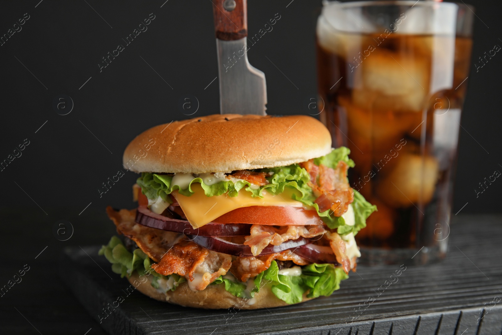 Photo of Tasty burger with bacon and cola served on board, closeup