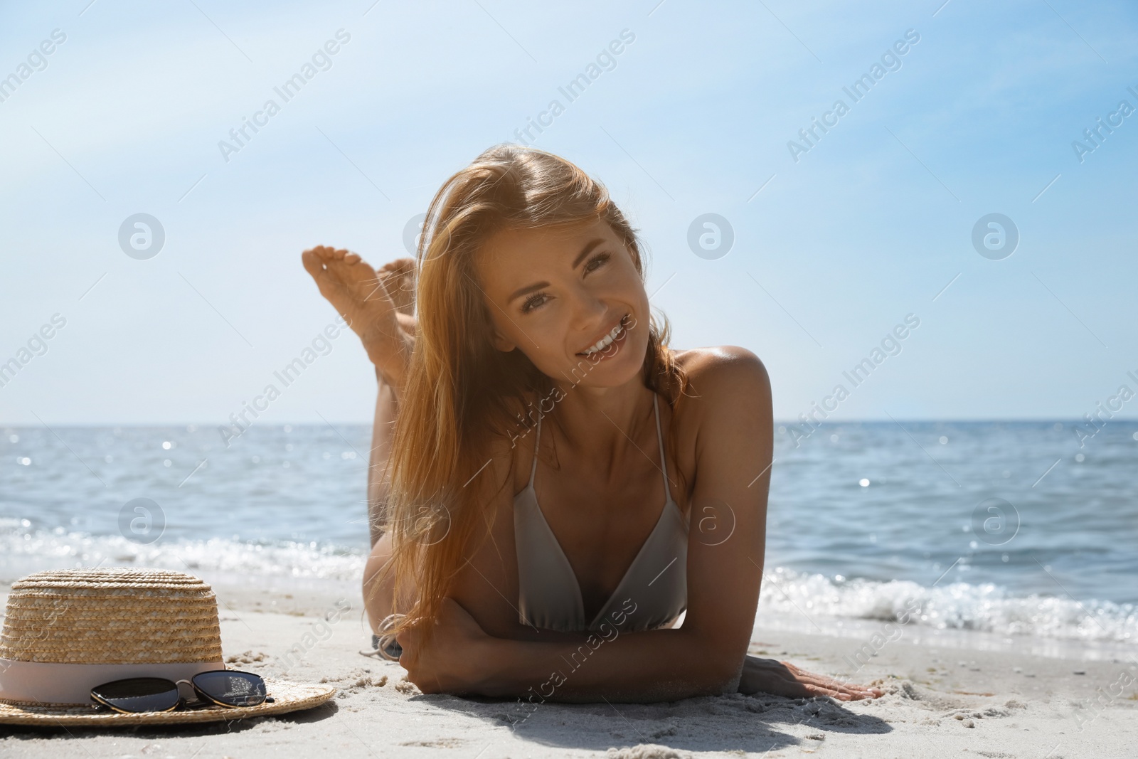 Photo of Attractive woman in bikini lying on sandy beach near sea