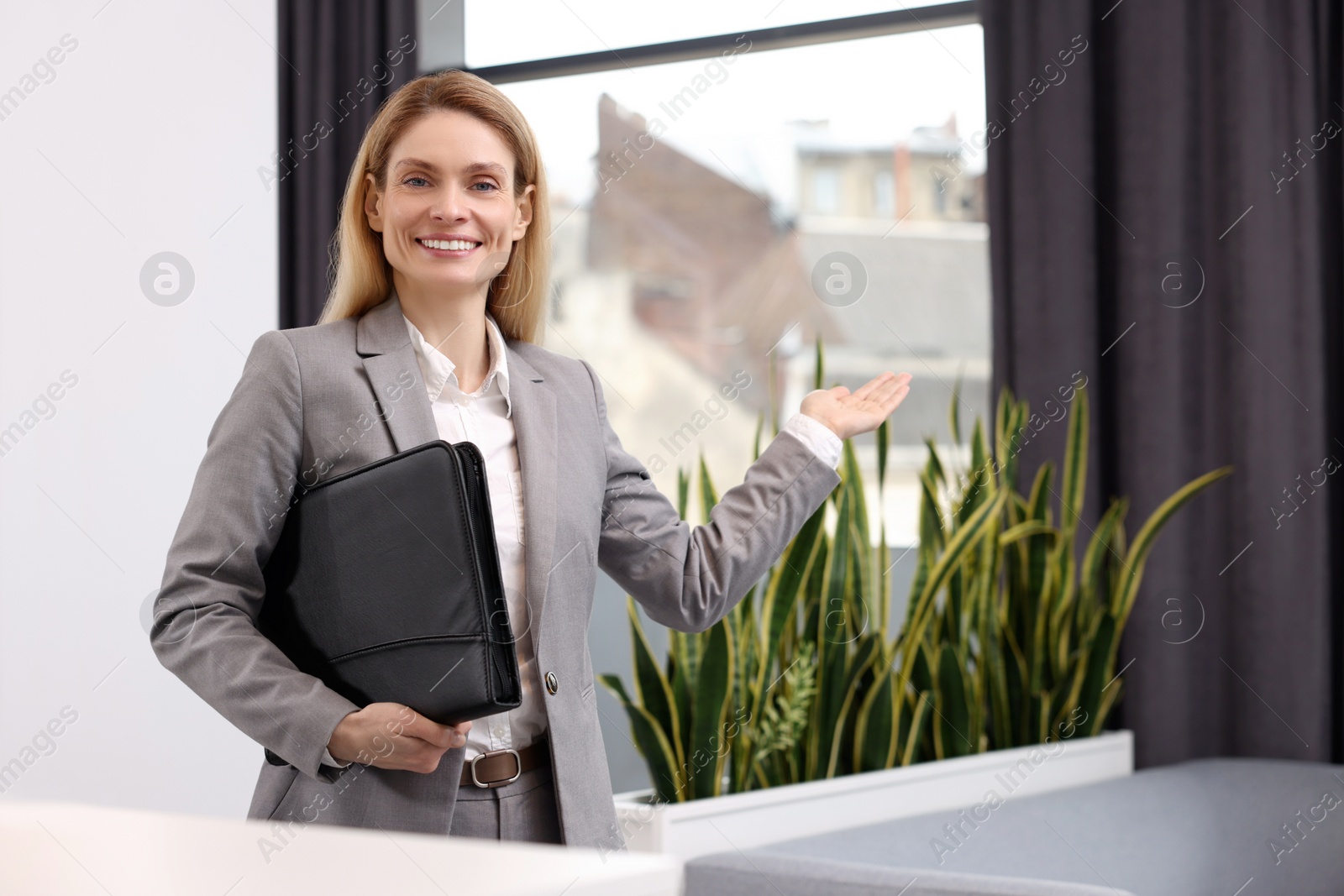 Photo of Happy real estate agent with leather portfolio indoors. Space for text