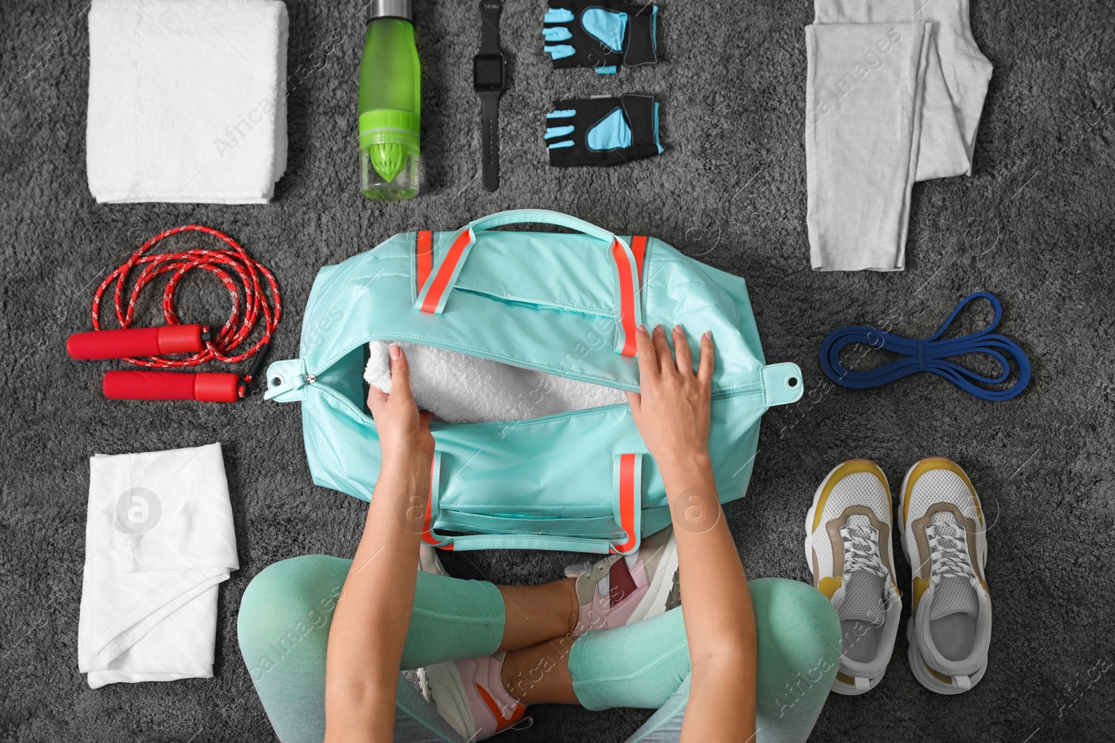 Photo of Woman with bag and sports items on grey carpet, top view