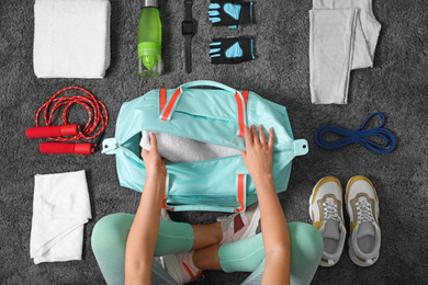 Woman with bag and sports items on grey carpet, top view