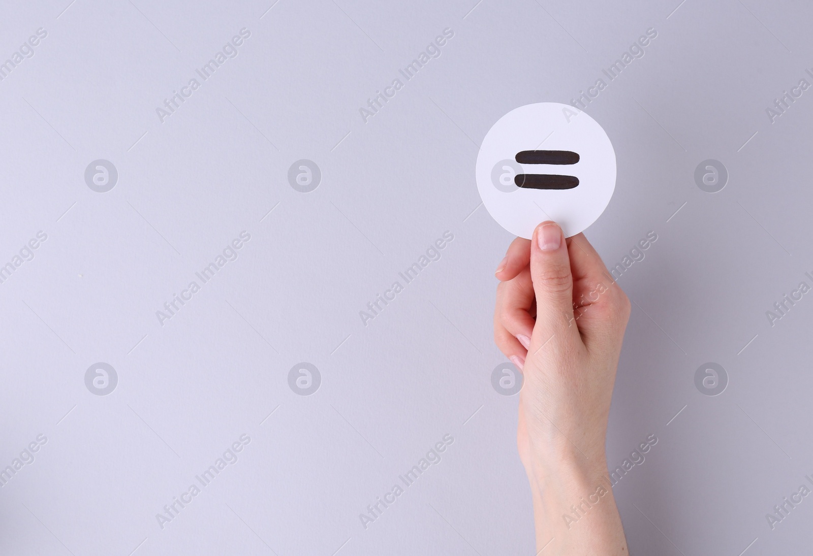 Photo of Woman holding equals sign on light background, closeup. Space for text