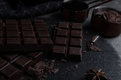 Photo of Tasty dark chocolate bars on black slate board