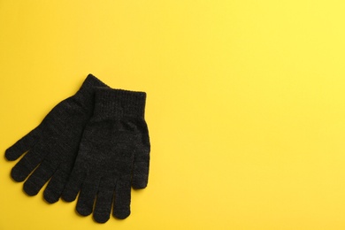 Photo of Pair of stylish woolen gloves on yellow background, flat lay. Space for text