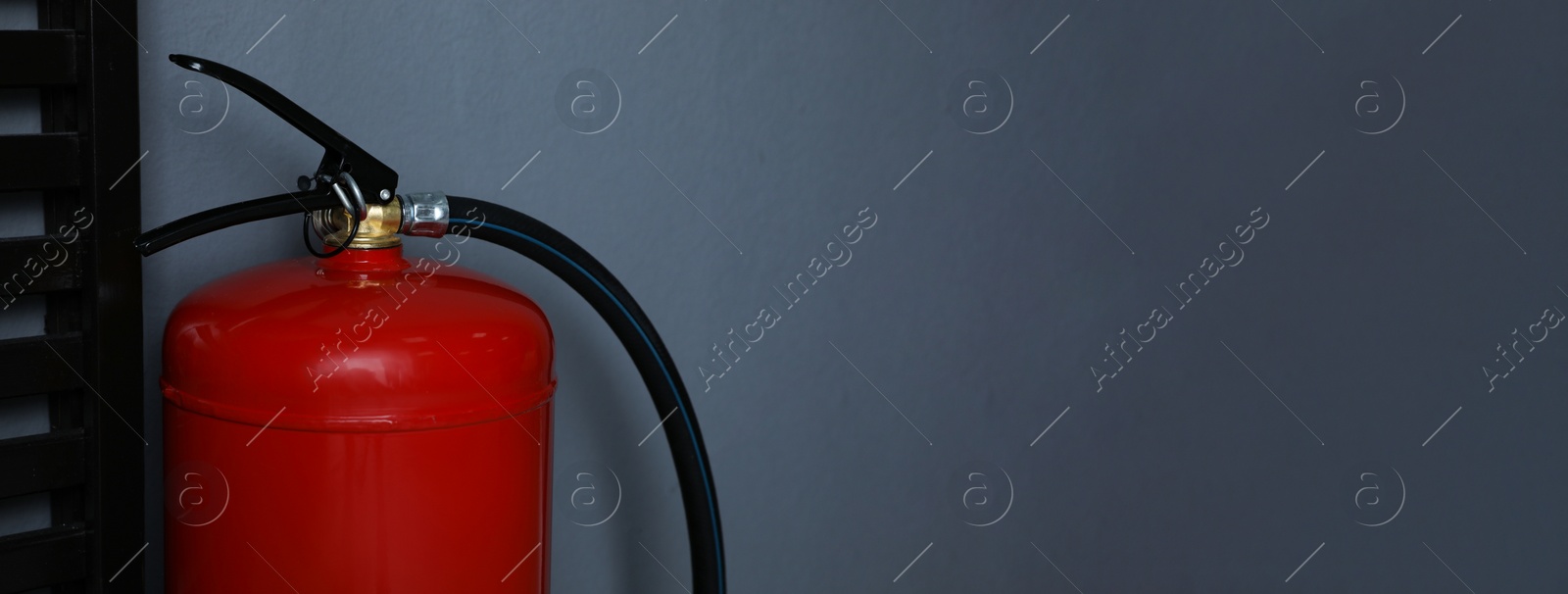 Image of Fire extinguisher near grey wall indoors, space for text. Banner design