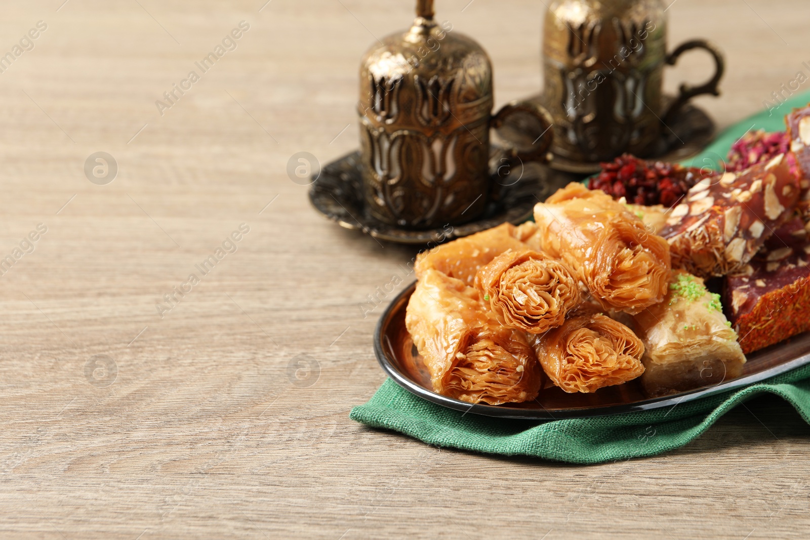 Photo of Tea, baklava dessert and Turkish delight served in vintage tea set on wooden table, space for text