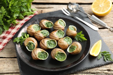 Photo of Delicious cooked snails served on wooden table