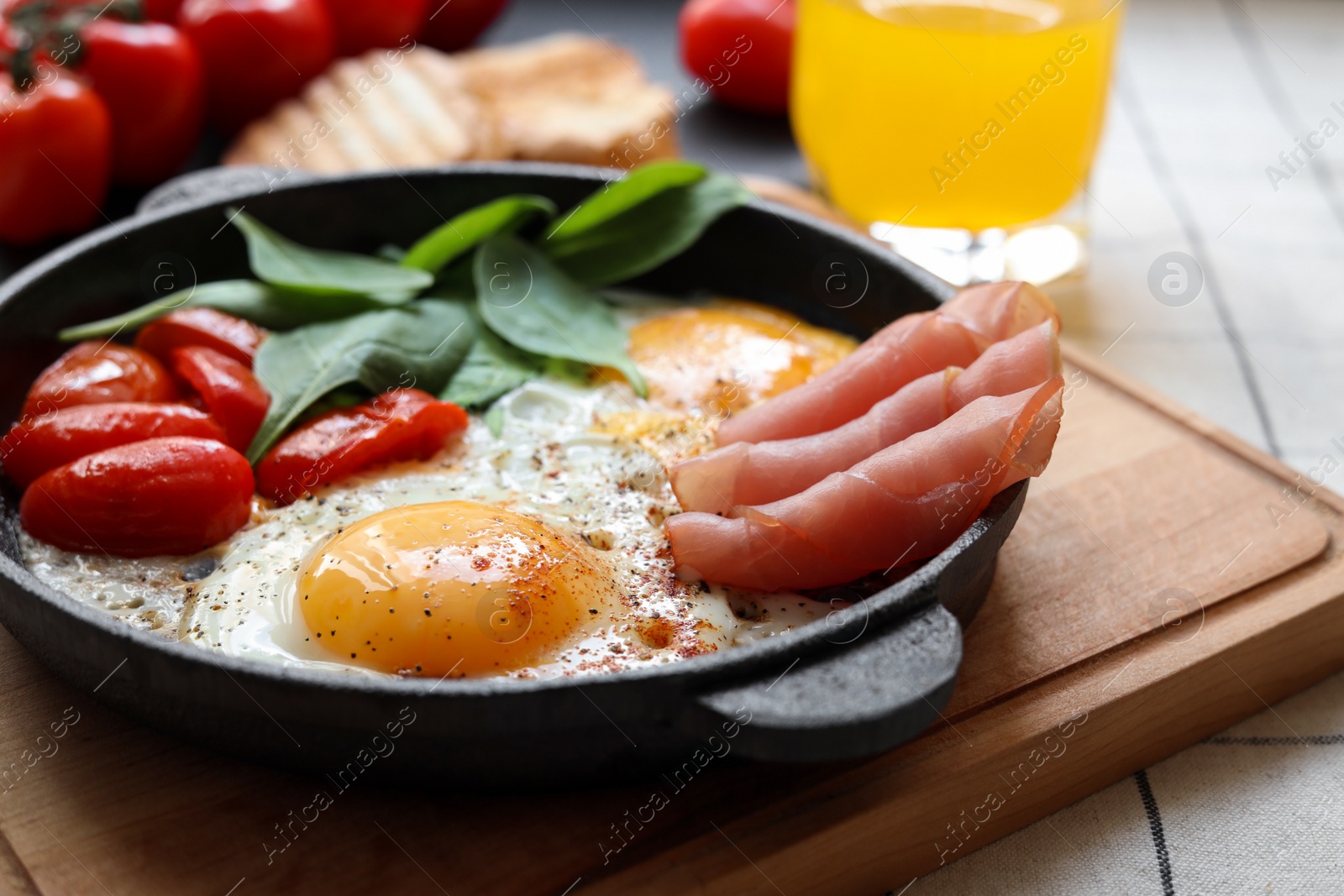 Photo of Delicious fried eggs with spinach, tomatoes and ham served on table, closeup