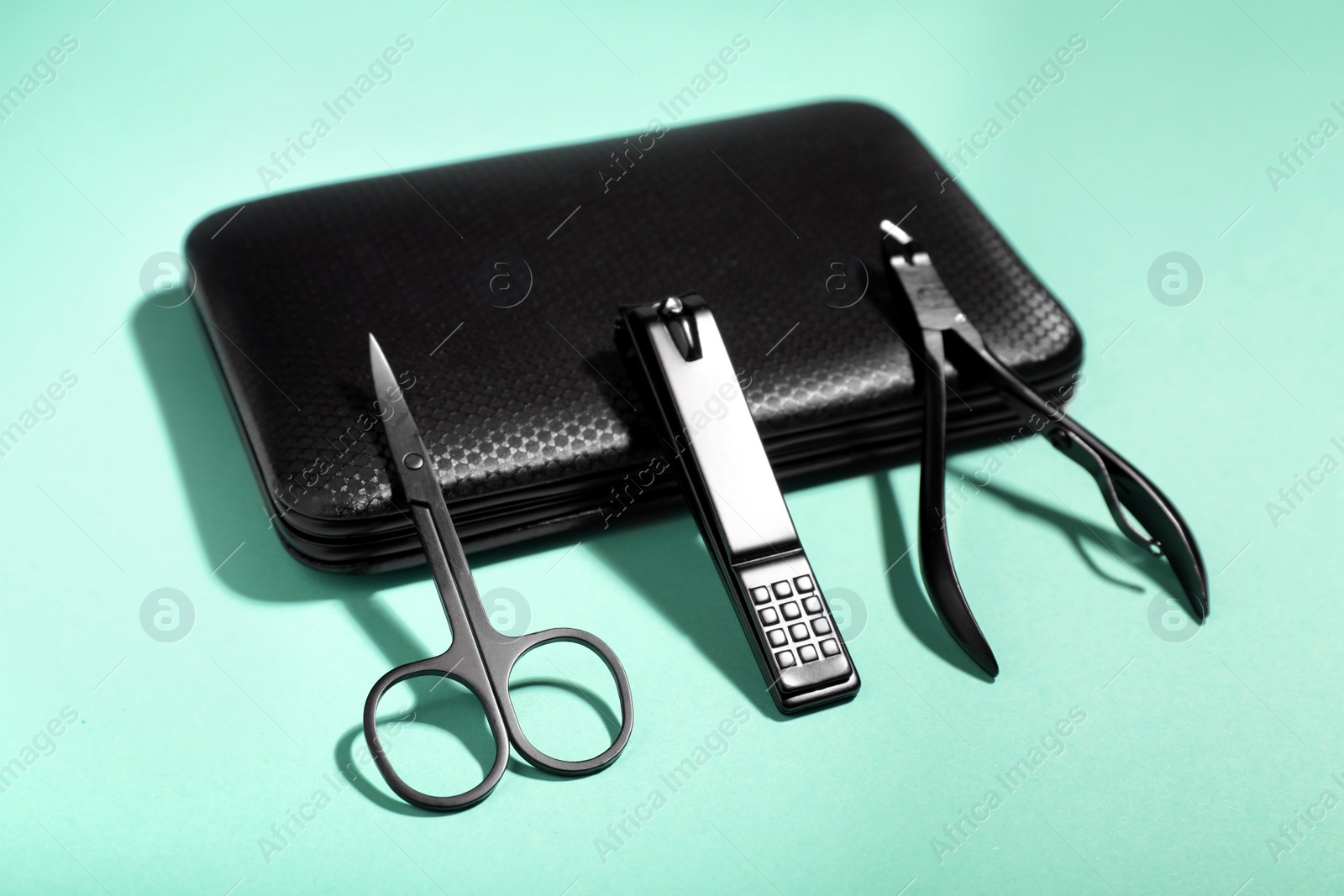 Photo of Set of manicure tools near case on turquoise background, closeup