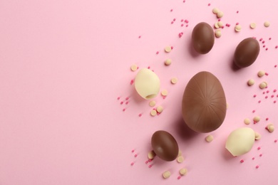 Photo of Sweet chocolate eggs on pink background, flat lay. Space for text