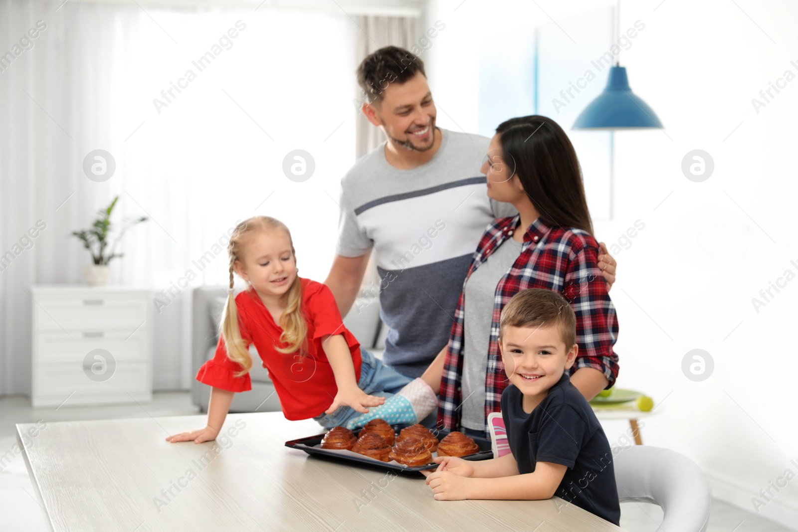 Photo of Happy family with tray of oven baked buns in kitchen