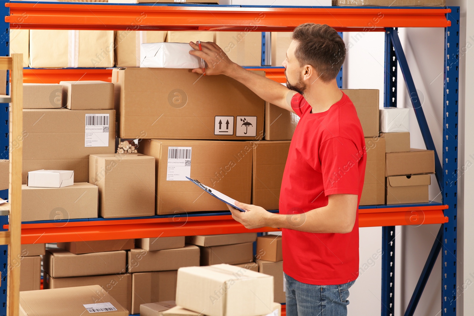 Photo of Post office worker with clipboard checking parcels at rack indoors