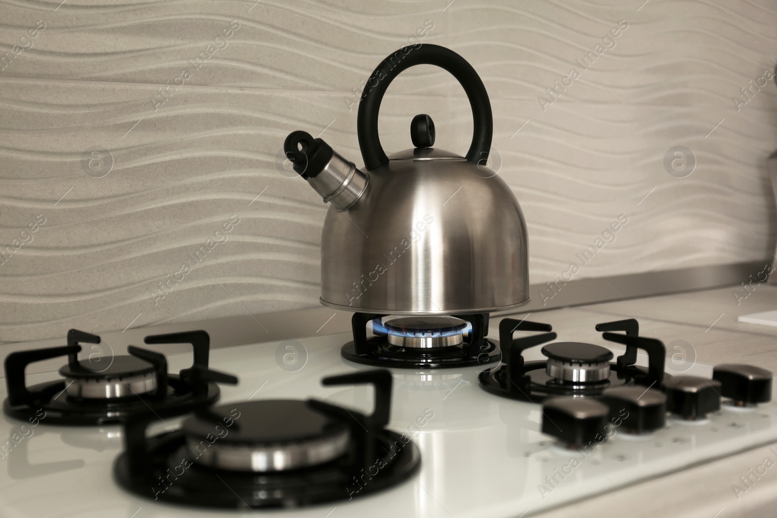 Photo of Steel kettle with whistle on modern gas stove