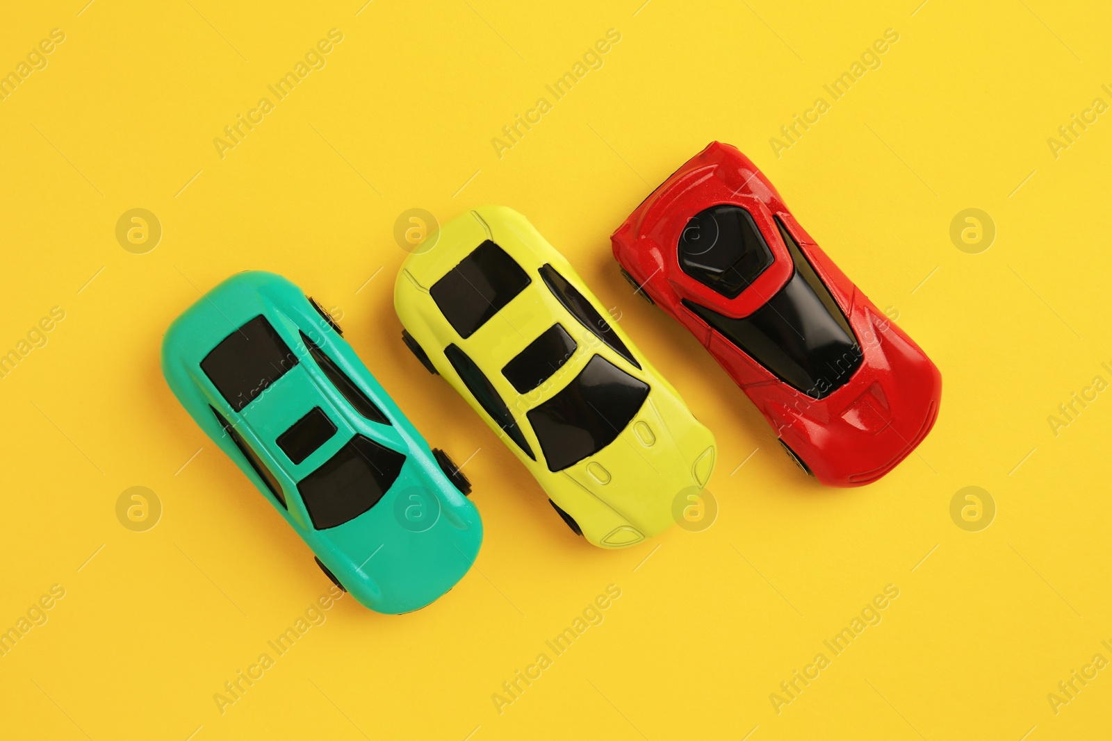 Photo of Different bright cars on yellow background, flat lay. Children`s toys