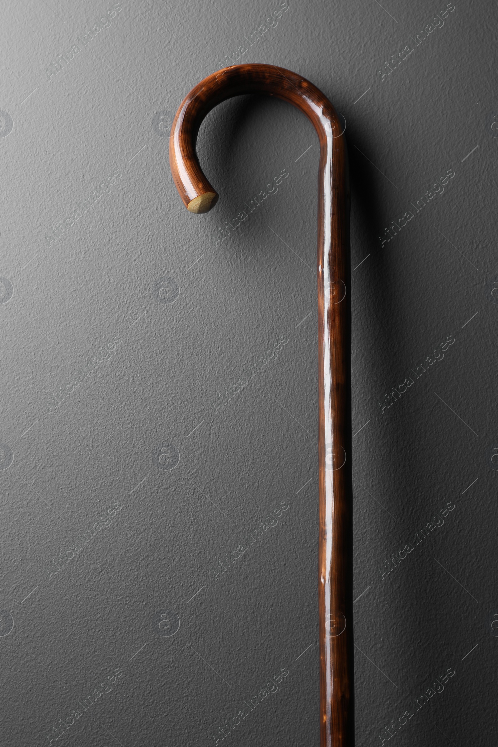 Photo of Elegant wooden walking cane on grey background