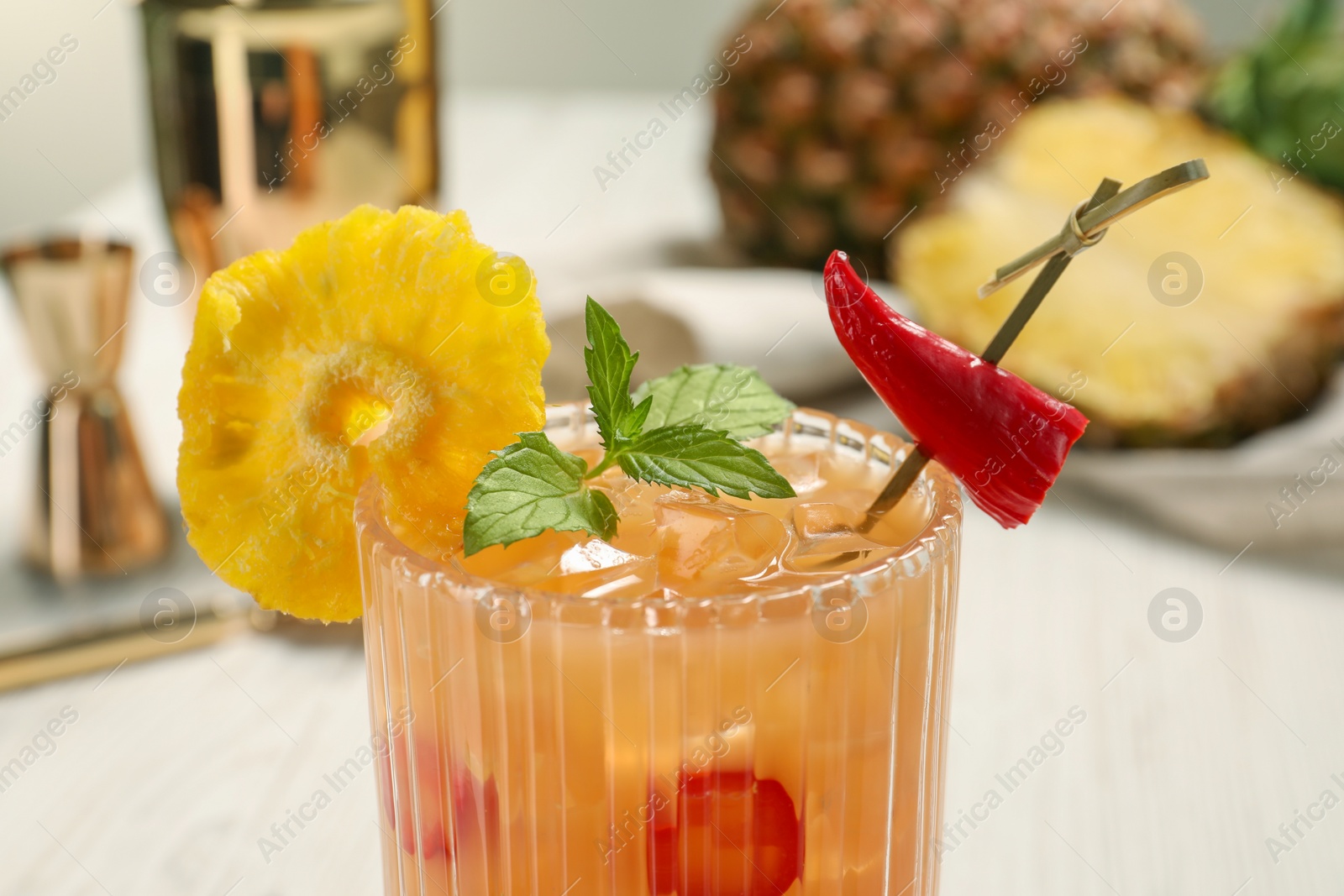 Photo of Glass of spicy pineapple cocktail with chili pepper and mint on light background, closeup