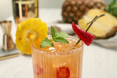 Glass of spicy pineapple cocktail with chili pepper and mint on light background, closeup