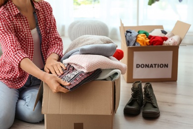 Photo of Woman packing clothes into donation box at home