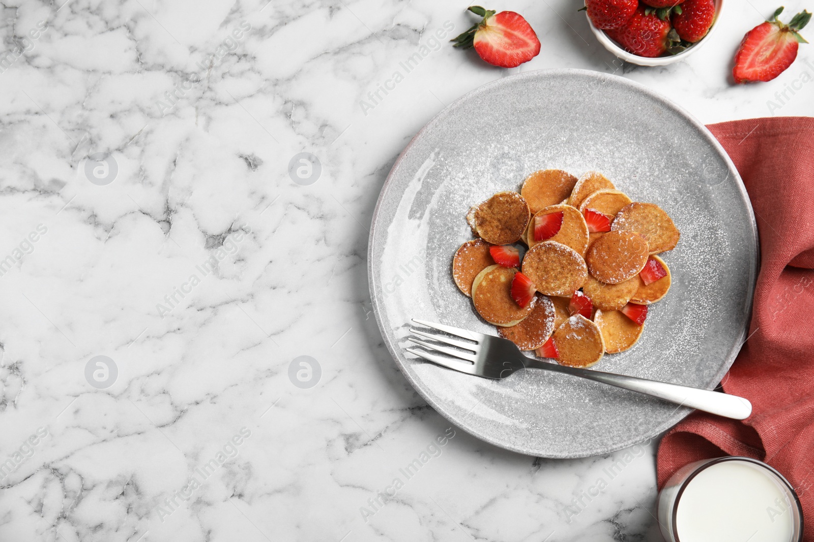 Photo of Delicious mini pancakes cereal with strawberries served on white marble table, flat lay. Space for text