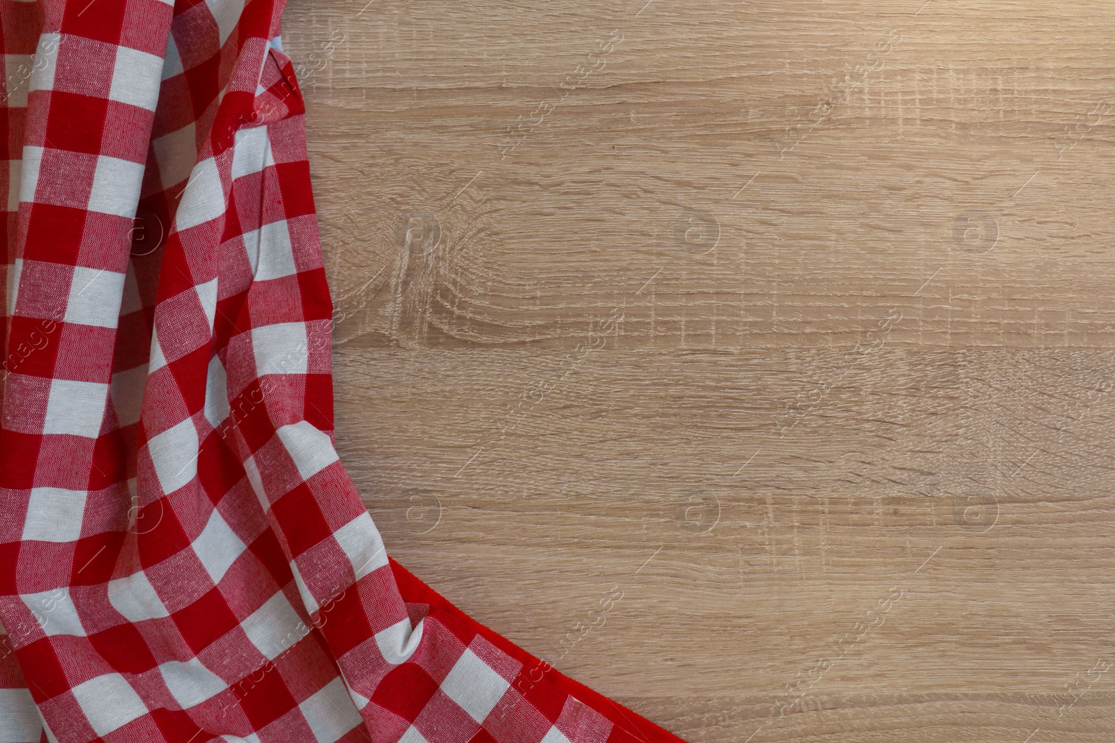 Photo of Checkered picnic cloth on wooden table, top view. Space for text