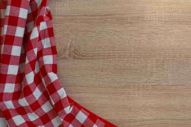 Photo of Checkered picnic cloth on wooden table, top view. Space for text