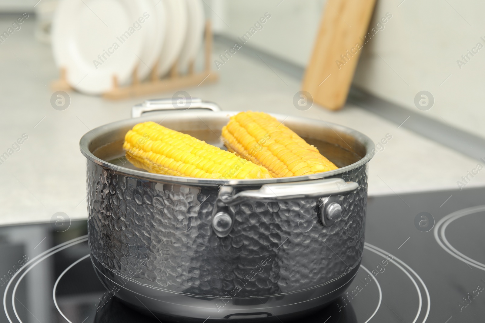 Photo of Pot with boiling corn on induction cooktop