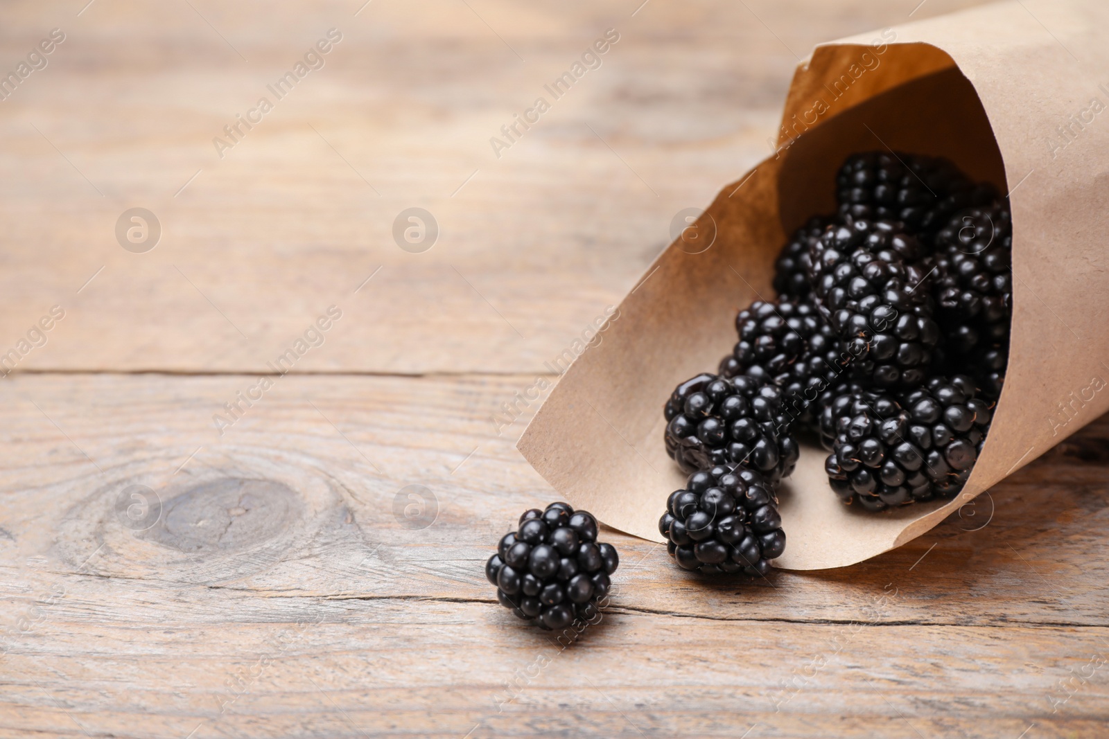 Photo of Fresh ripe blackberries on wooden table. Space for text