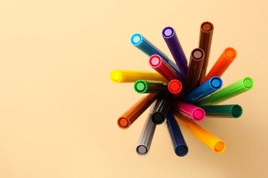 Photo of Many bright markers on beige background, top view. Space for text