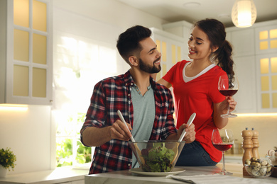 Photo of Lovely young couple cooking salad together in kitchen