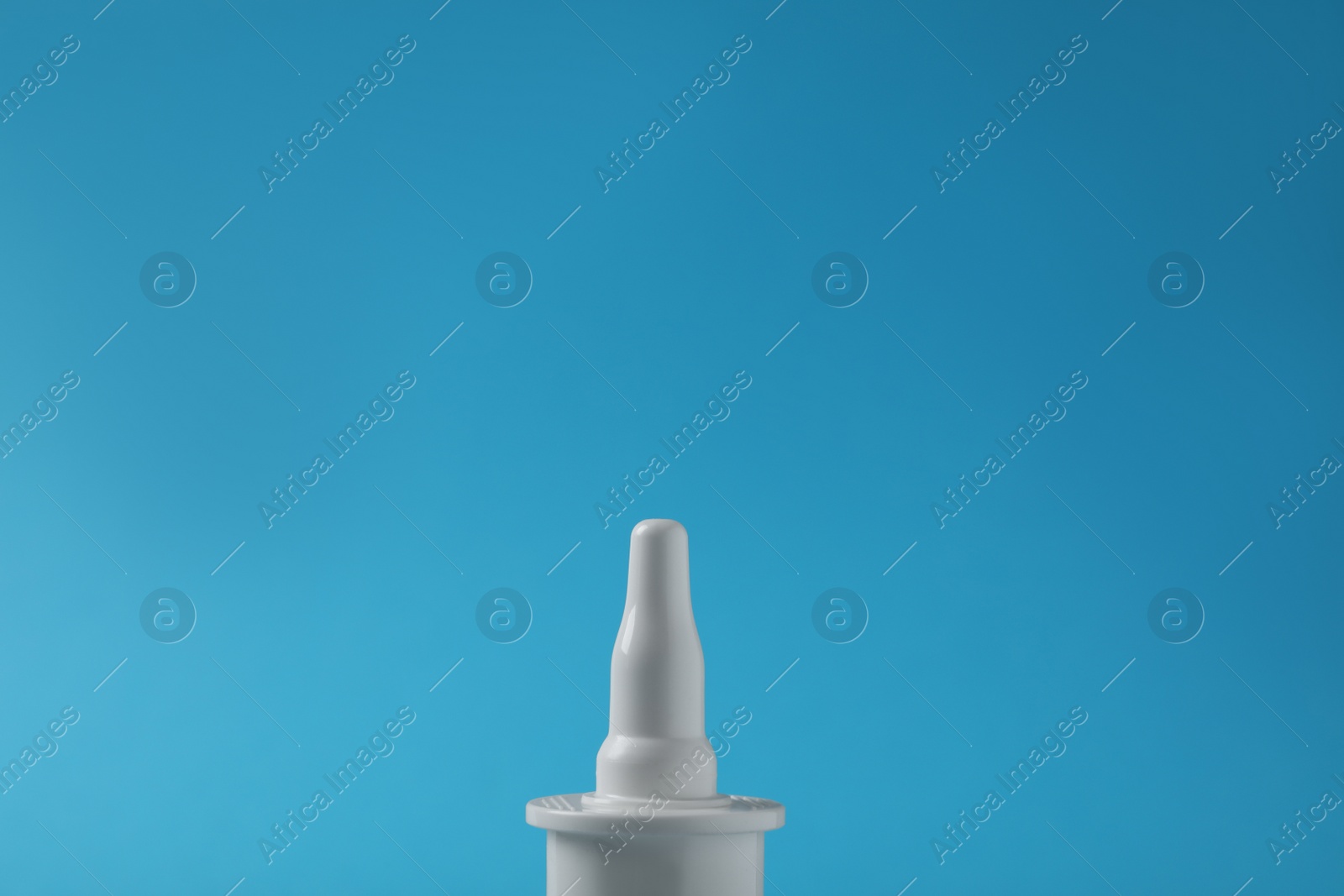 Photo of Bottle of nasal spray on light blue background, closeup. Space for text