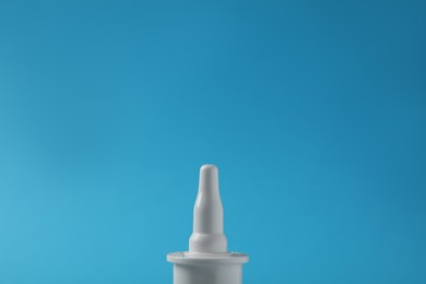 Bottle of nasal spray on light blue background, closeup. Space for text