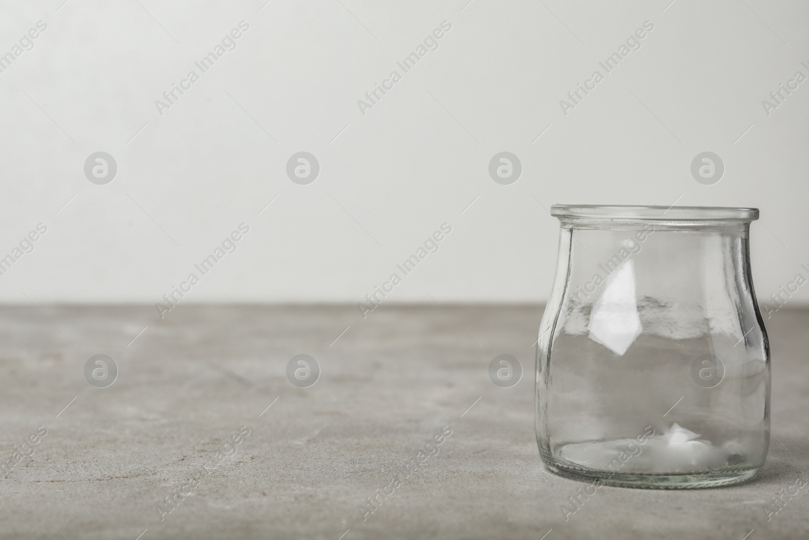 Photo of Empty glass jar on grey table, space for text