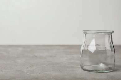 Photo of Empty glass jar on grey table, space for text