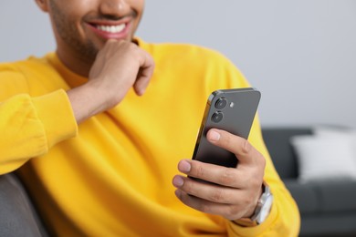 Man sending message via smartphone indoors, closeup