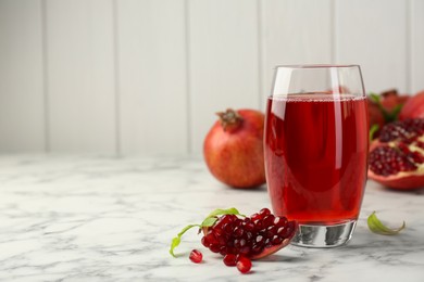 Photo of Tasty pomegranate juice in glass and fresh fruits on white marble table. Space for text