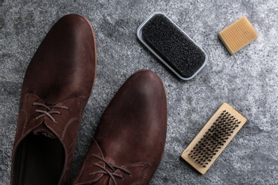 Stylish footwear with shoe care accessories on grey stone table, flat lay