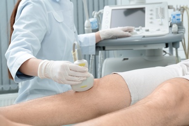 Photo of Doctor conducting ultrasound examination of patient's knee in clinic