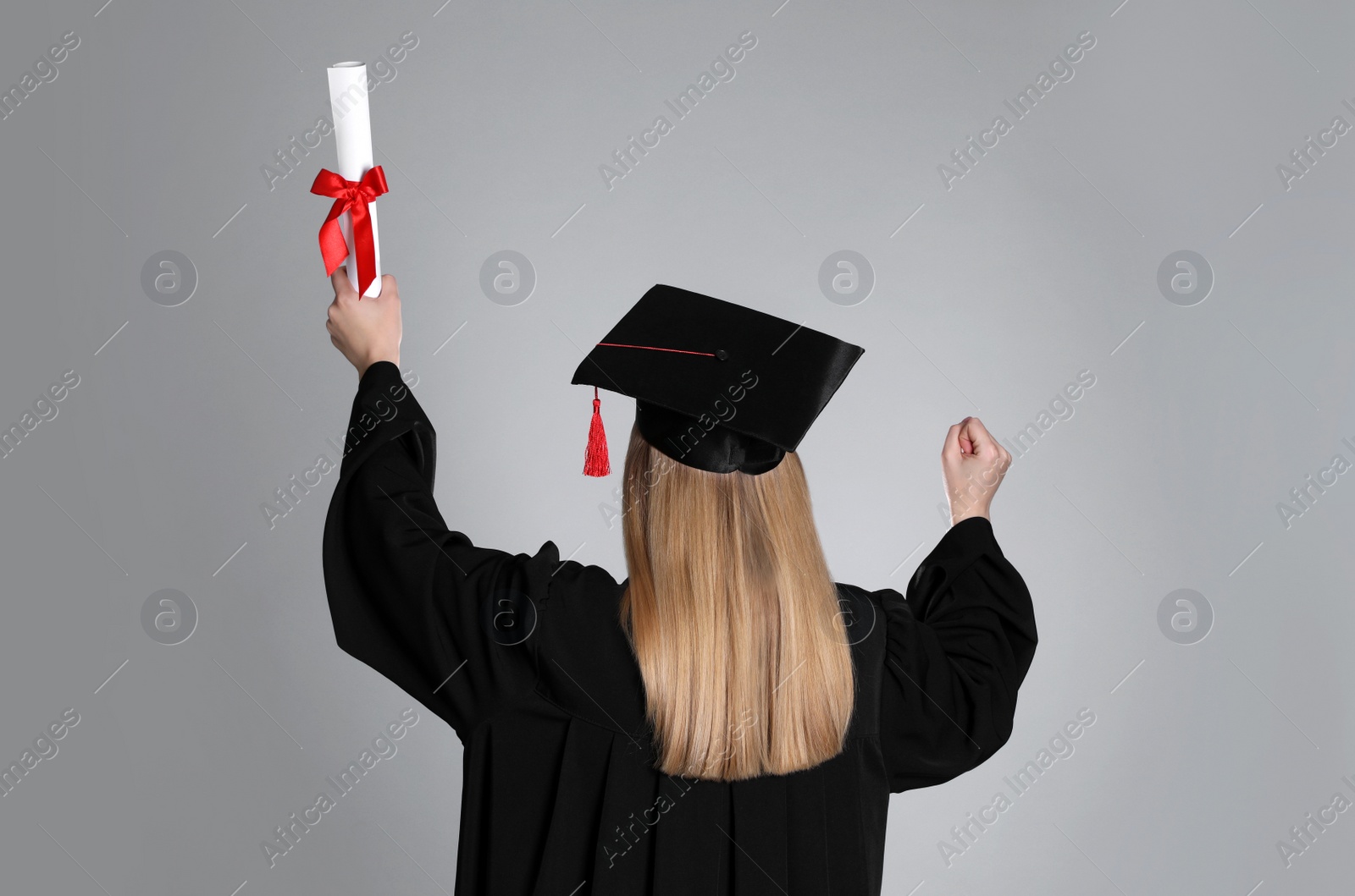 Photo of Student with diploma on grey background, back view