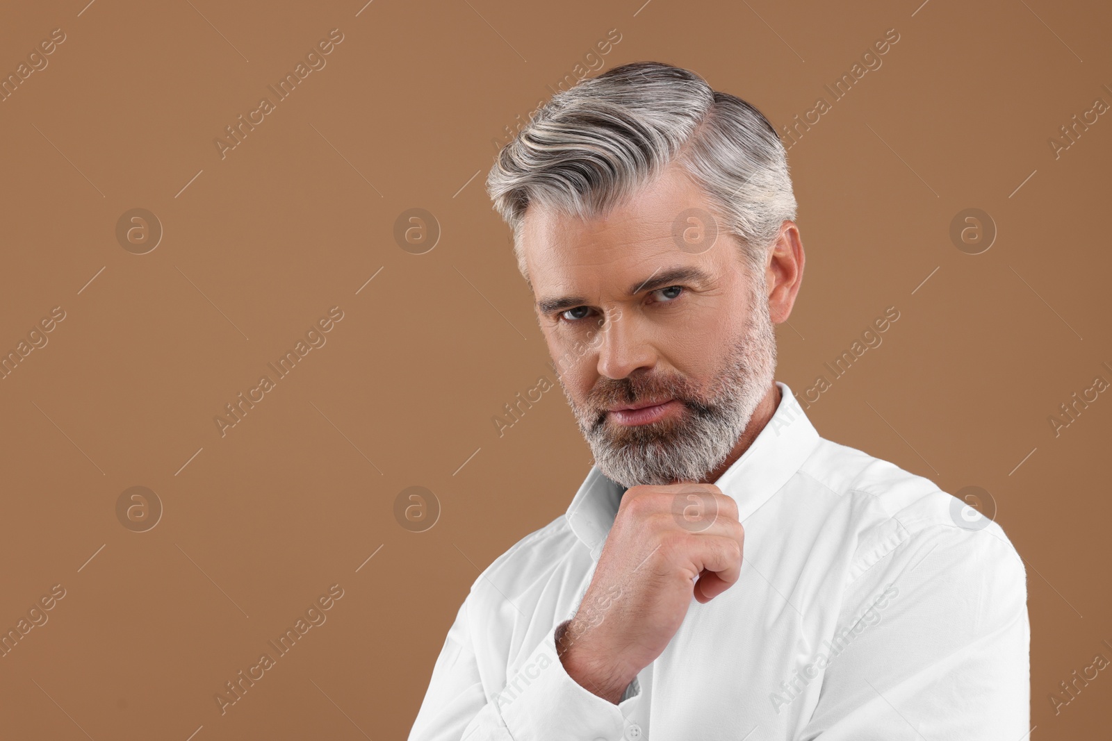 Photo of Portrait of confident man with beautiful hairstyle on light brown background. Space for text