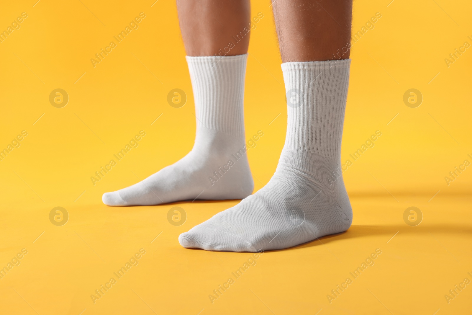 Photo of Man in stylish white socks on yellow background, closeup