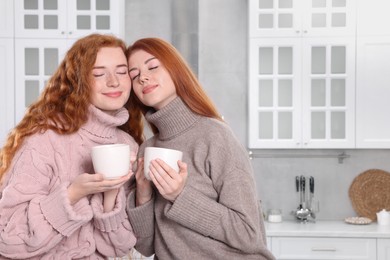 Photo of Portrait of beautiful young redhead sisters in kitchen. Space for text