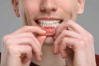 Man showing his clean teeth on light grey background, closeup