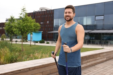 Photo of Man practicing Nordic walking with poles outdoors. Space for text