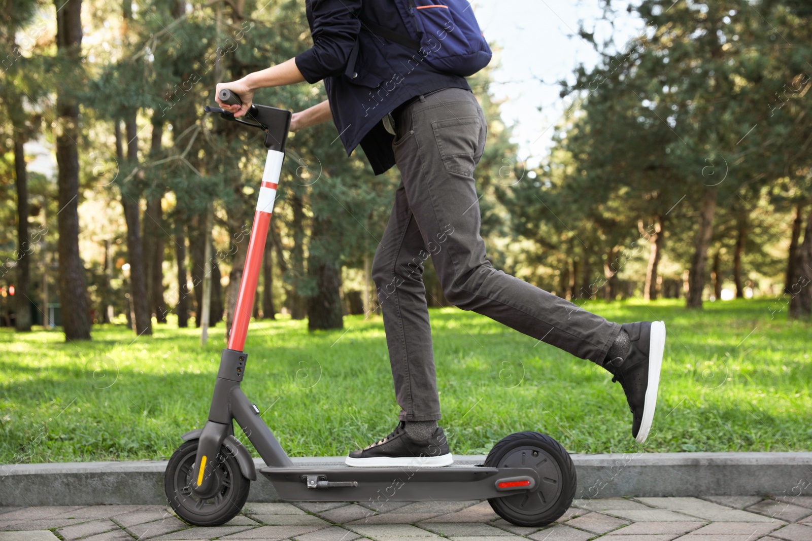 Photo of Man riding modern electric scooter in park, closeup