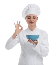 Photo of Happy woman chef in uniform holding bowl and showing OK gesture on white background