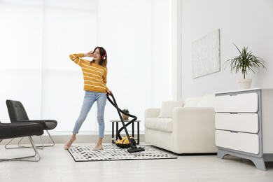 Young woman having fun while vacuuming at home