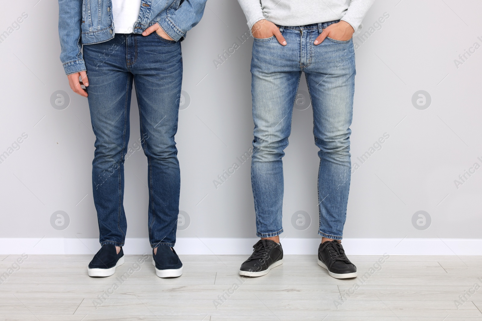 Photo of Men in stylish jeans near light grey wall indoors, closeup