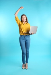 Photo of Emotional young woman with laptop celebrating victory on color background